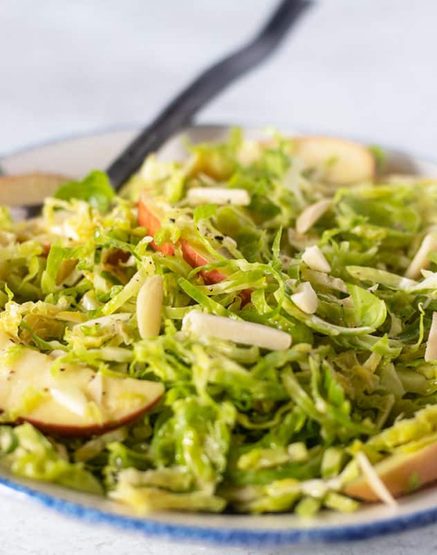 Shaved Brussel Sprouts Salad in a bowl with a serving spoon