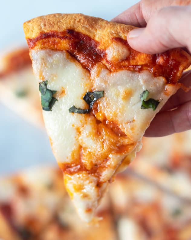 Holding a slice of coconut flour pizza crust