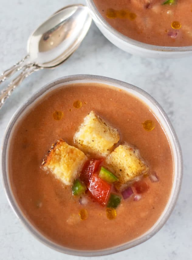 gazpacho soup in a bowl topped with croutons and extra chopped vegetables