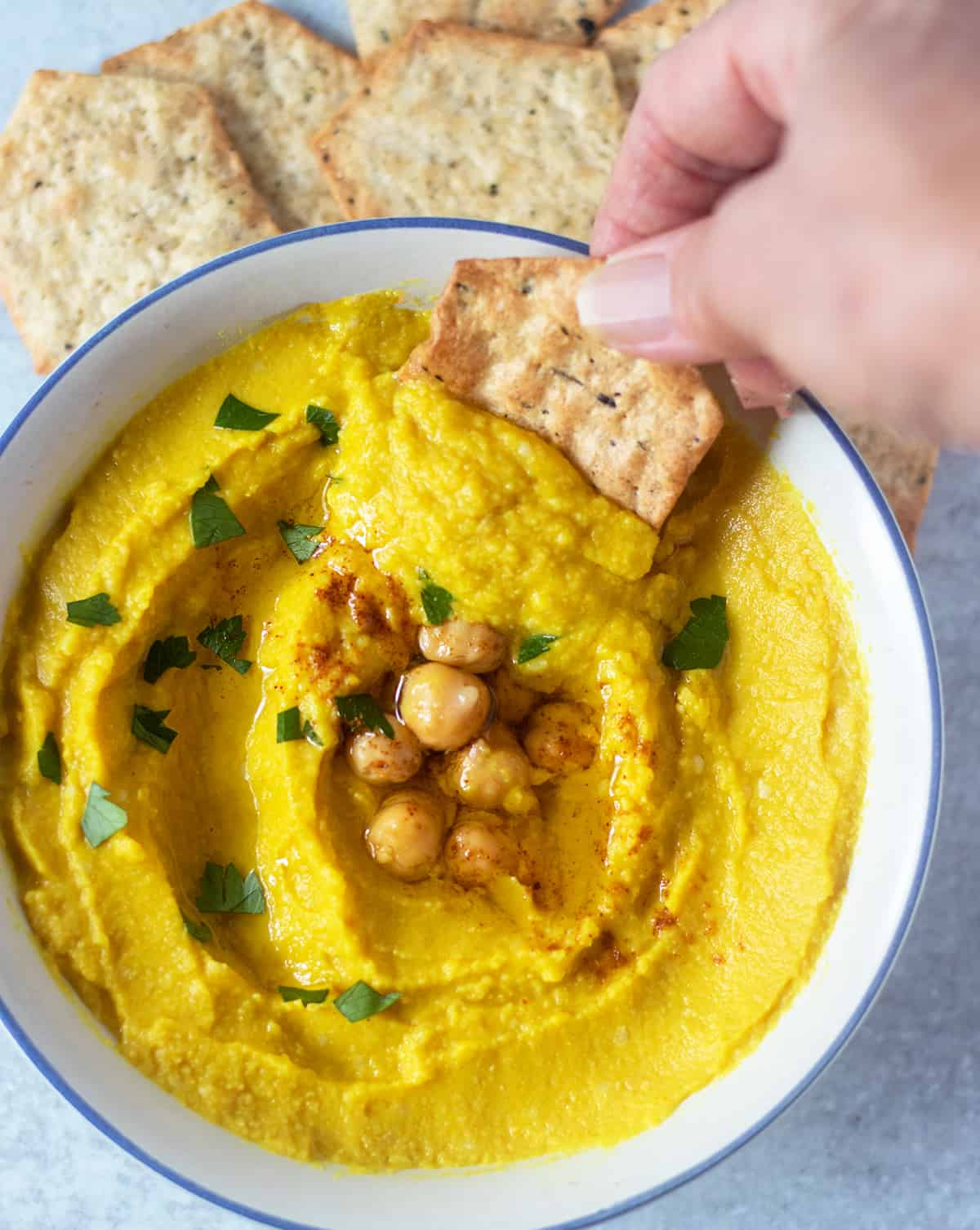 dipping out turmeric hummus with cracker