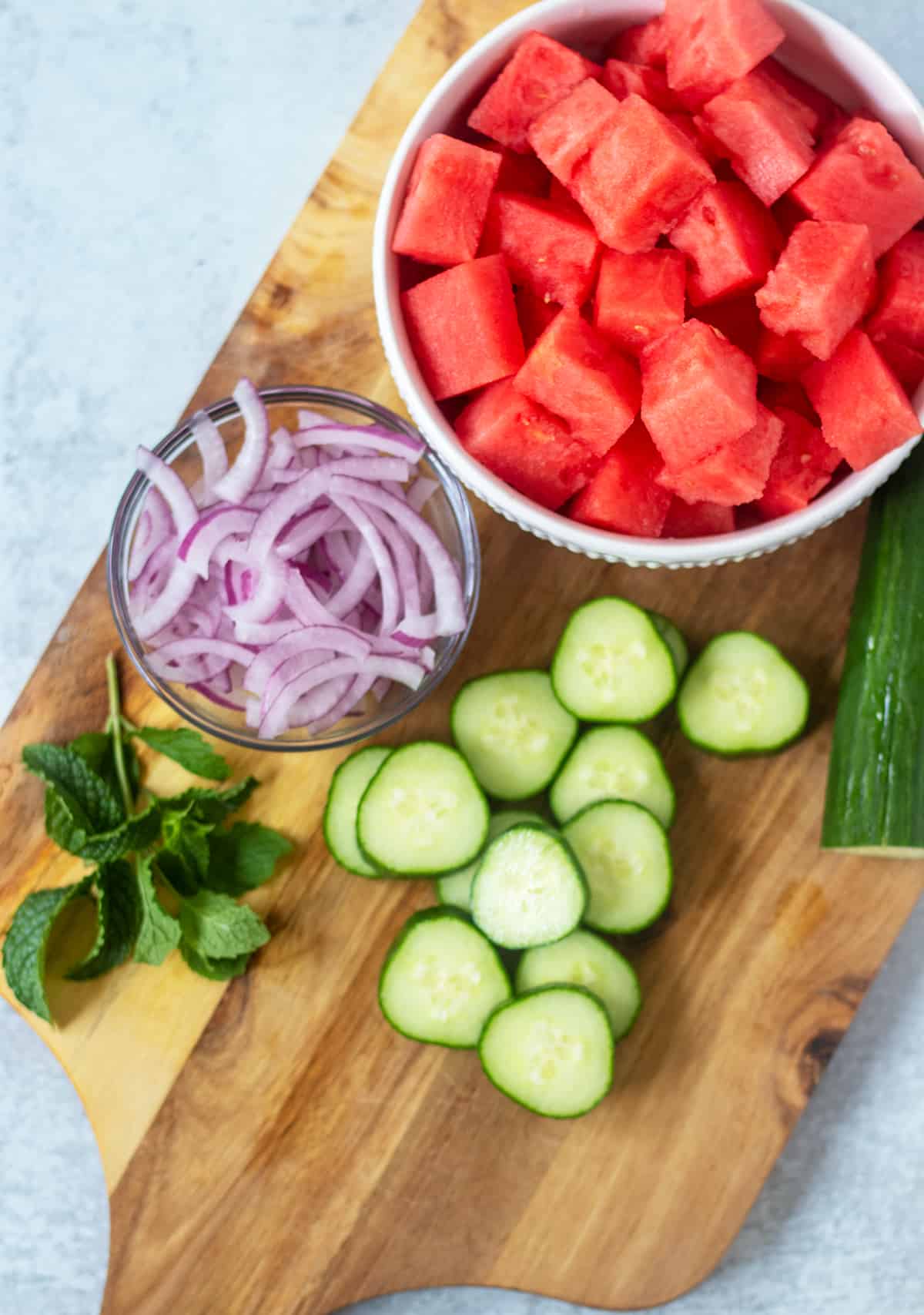 Cubed watermelon, sliced cucumber , red onion, and fresh mint for watermelon cucumber salad