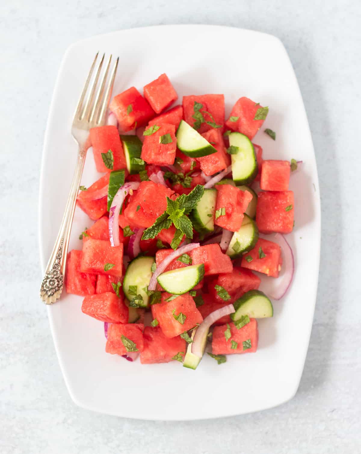 Watermelon Cucumber Salad on a white serving platter with a silver fork