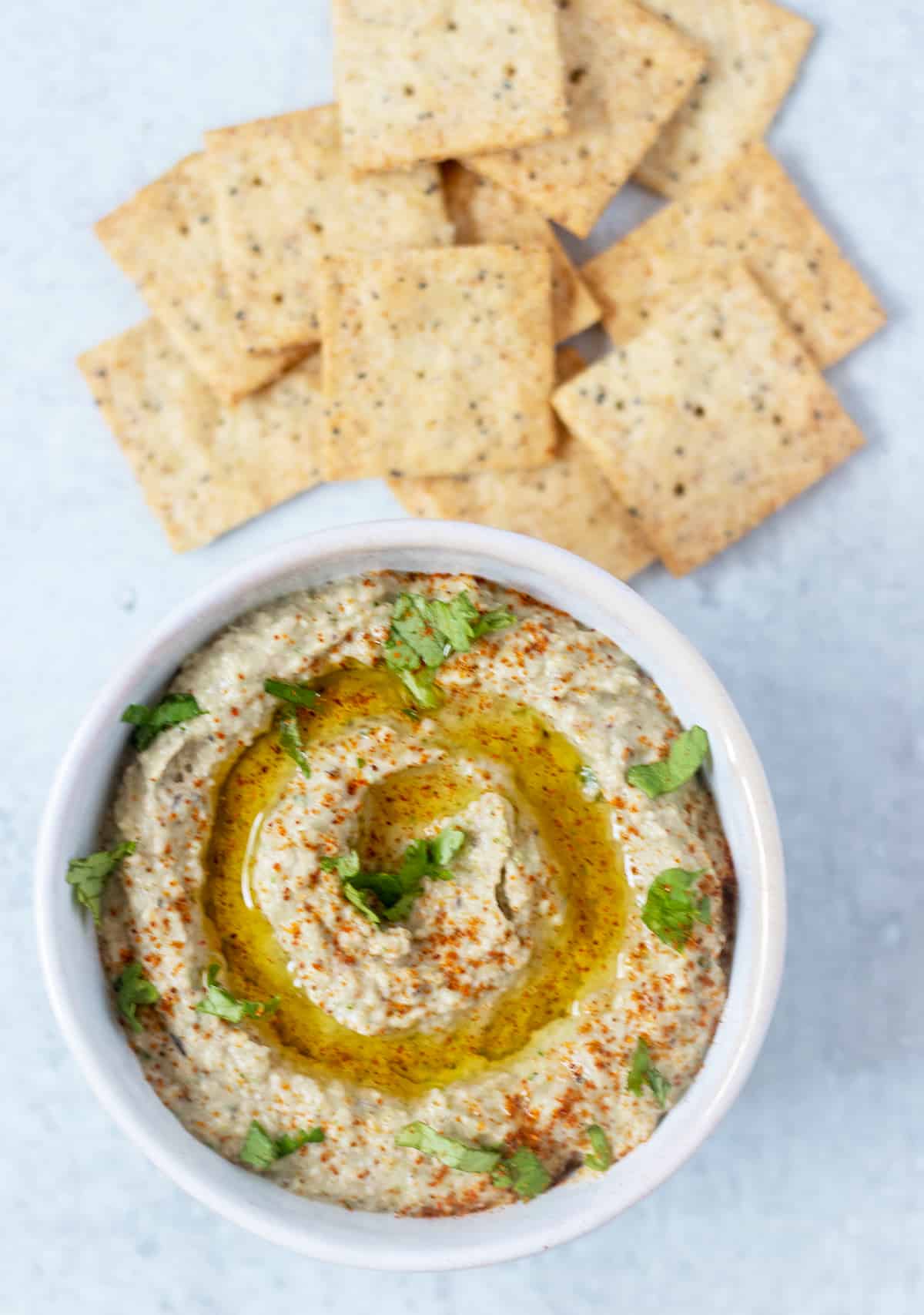 hummus in a bowl topped with cilantro, olive oil and paprika