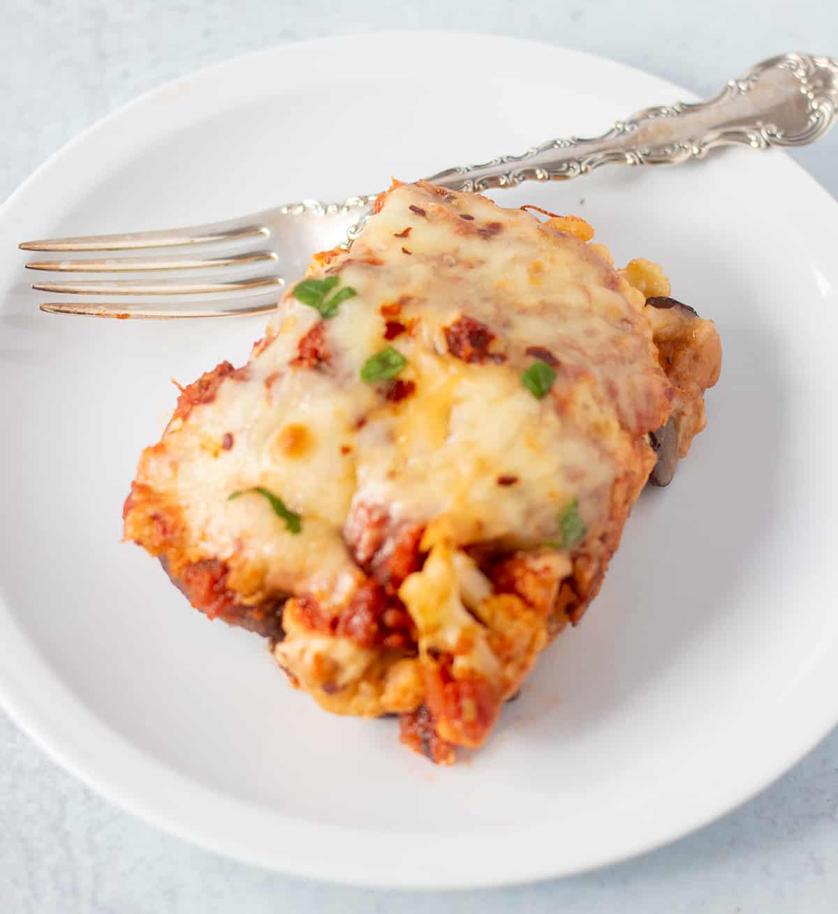 cauliflower marinara on a white plate with a silver fork