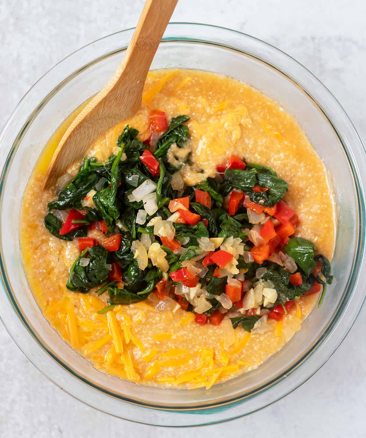 Cooked grits in mixing bowl with cooked veggies and remaining ingredients