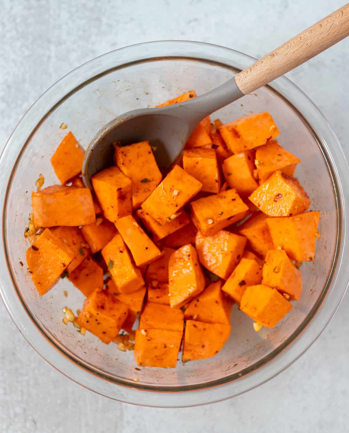 sweet potatoes in a mixing bowl with olive oil and seasonings
