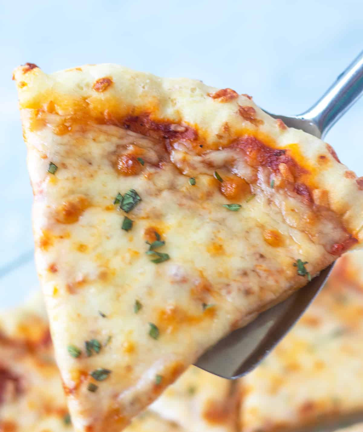 Cooked pizza slice being served with a stainless steel spatula