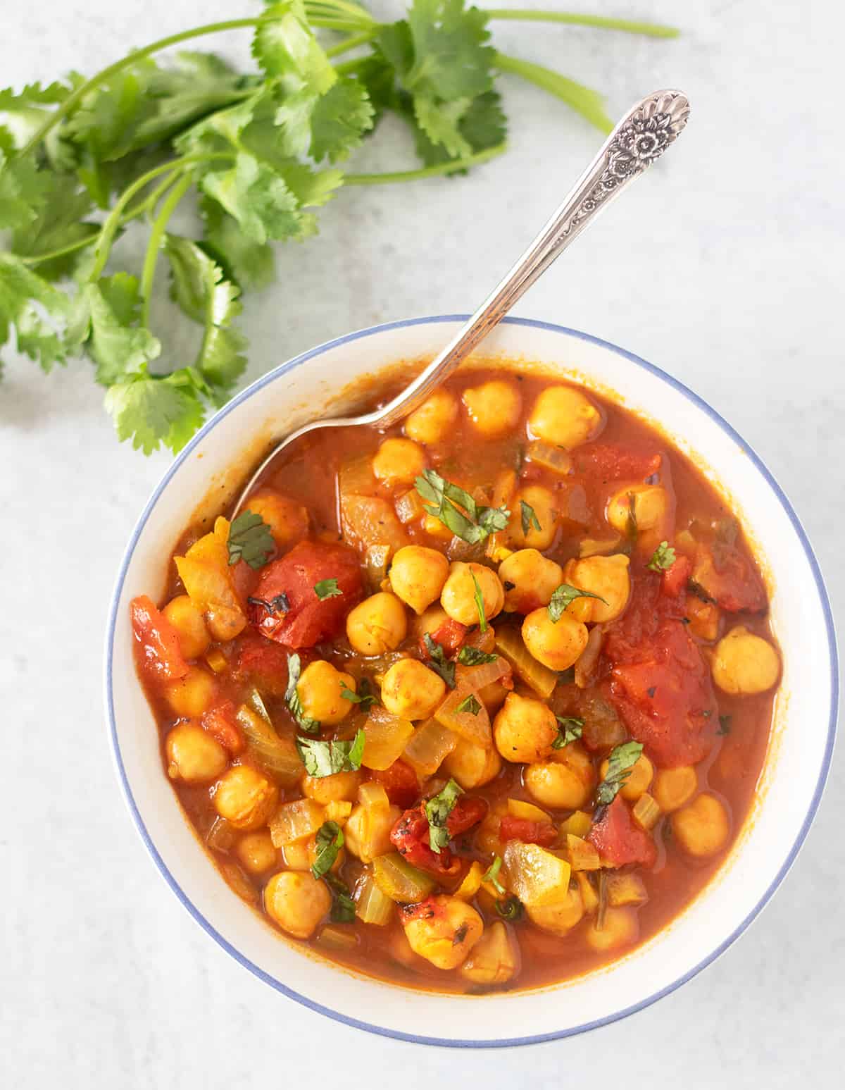 chickpea soup in a bowl with a silver spoon and topped with fresh cilantro