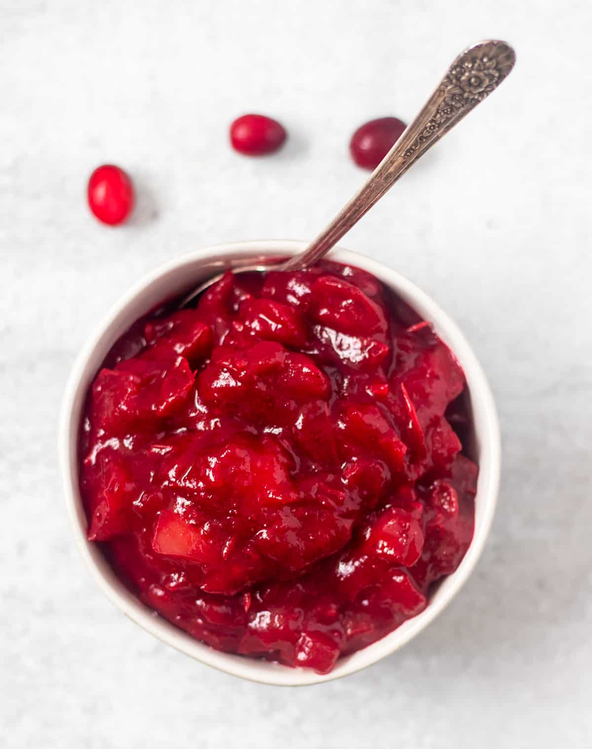 cranberry sauce in a white bowl with a silver spoon