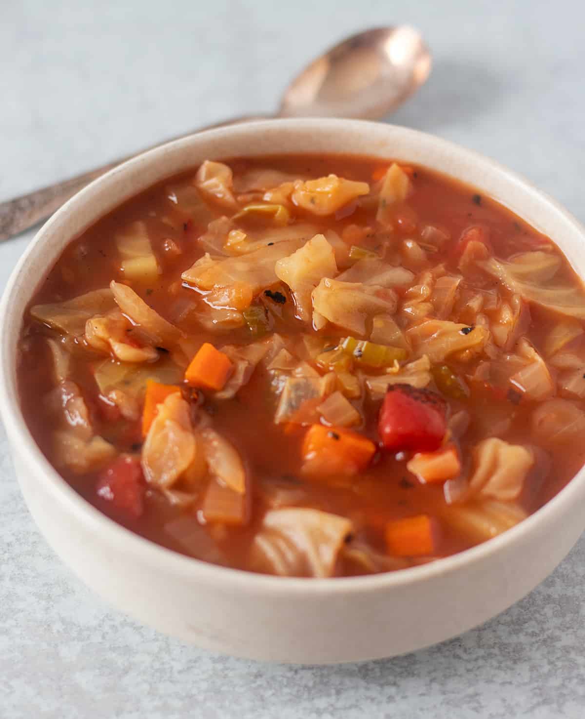 cabbage soup in a white bowl with a spoon next to the bowl