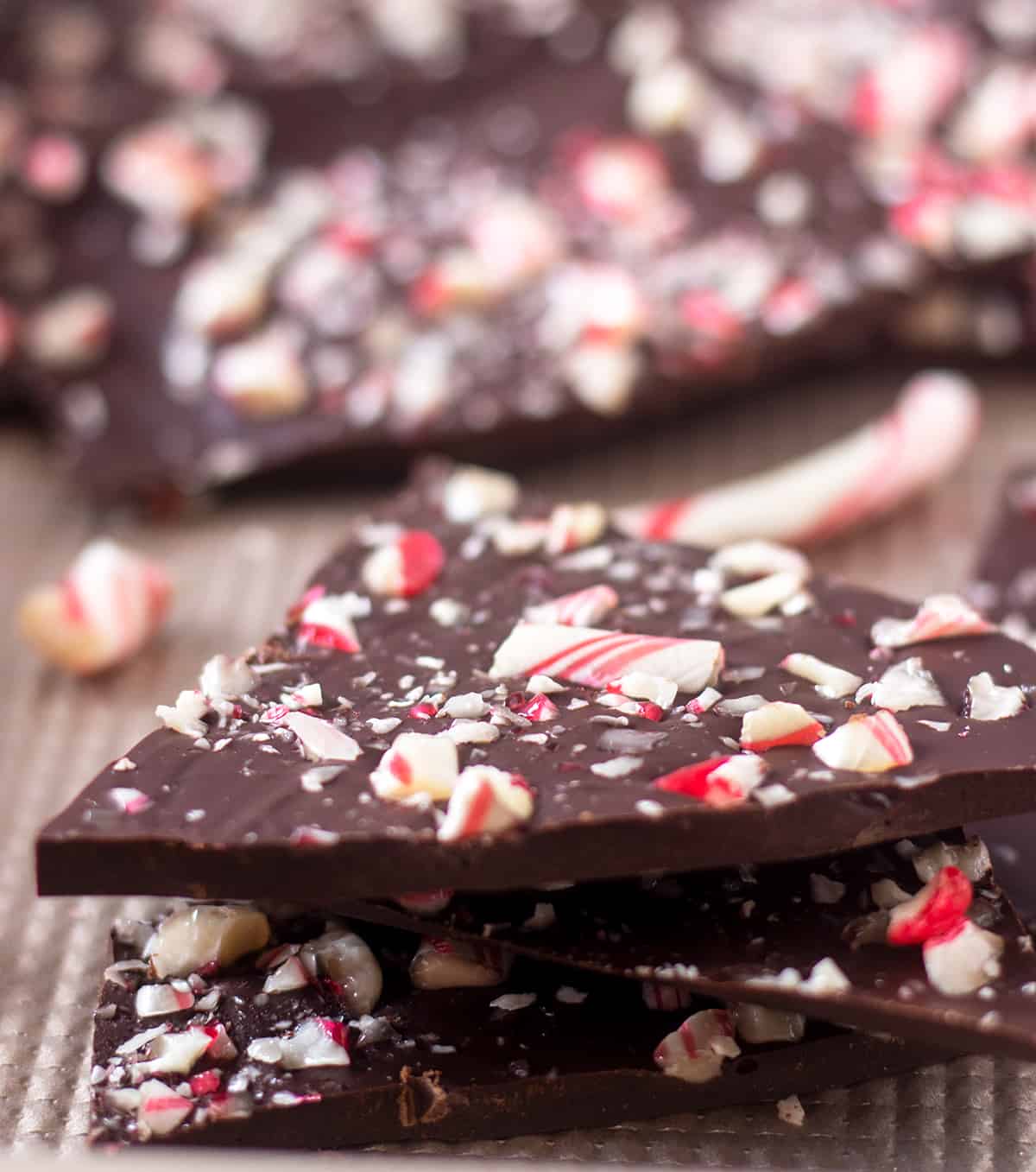 dark chocolate peppermint bark on rimmed pan and bark topped with crushed candy canes