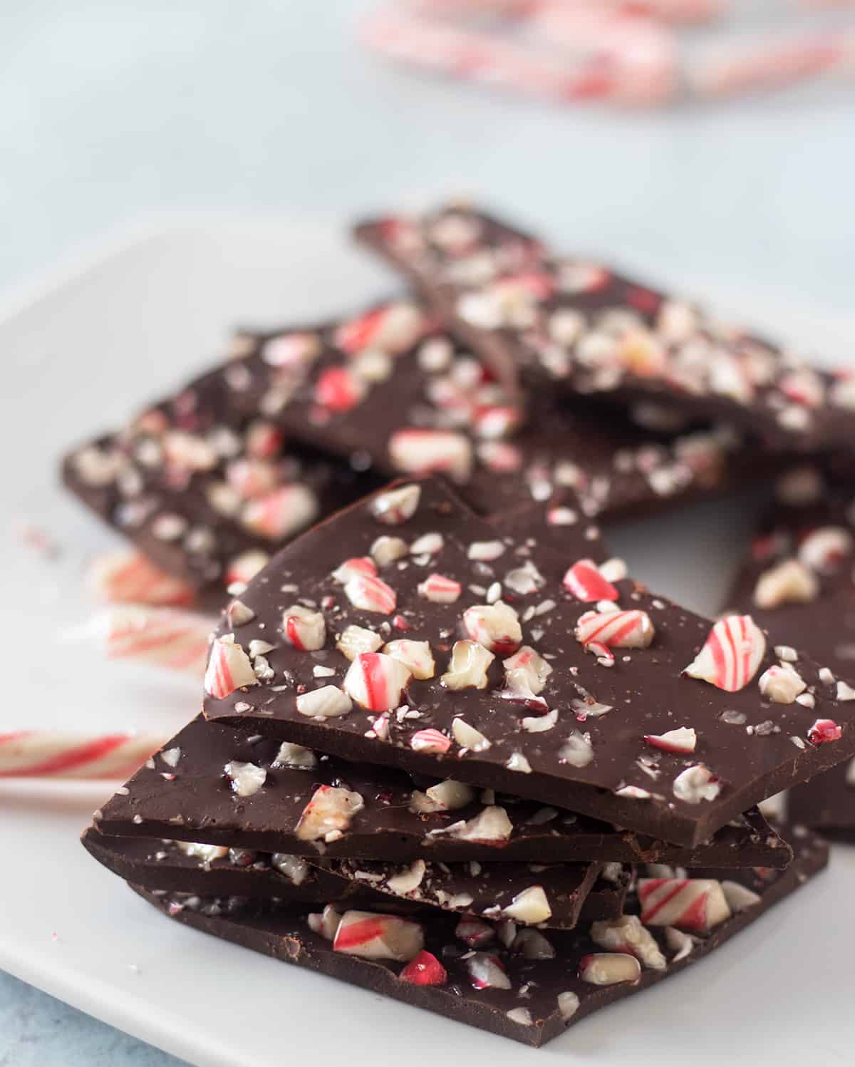 dark chocolate peppermint bark on a white plate with candy canes