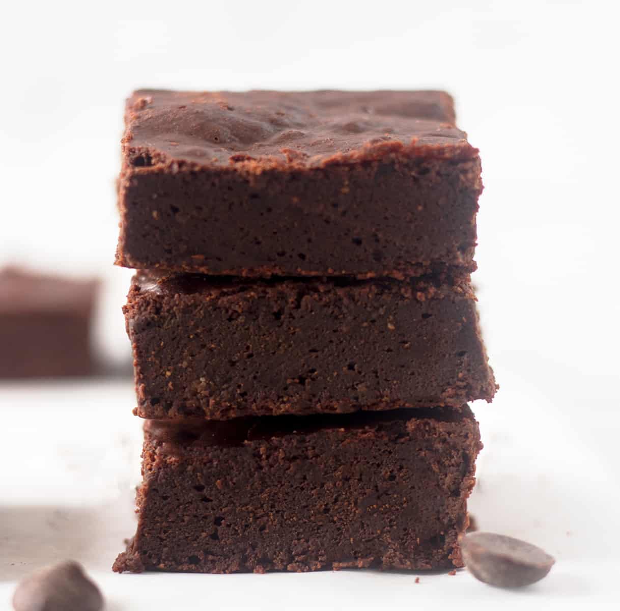 flourless brownies stacked on a parchment lined tray