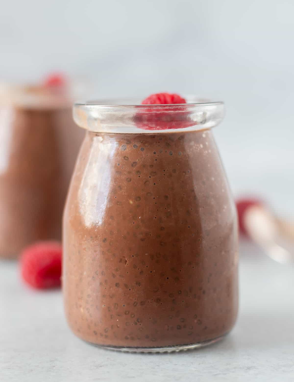 chocolate chia pudding in a glass jar garnished with a fresh raspberry