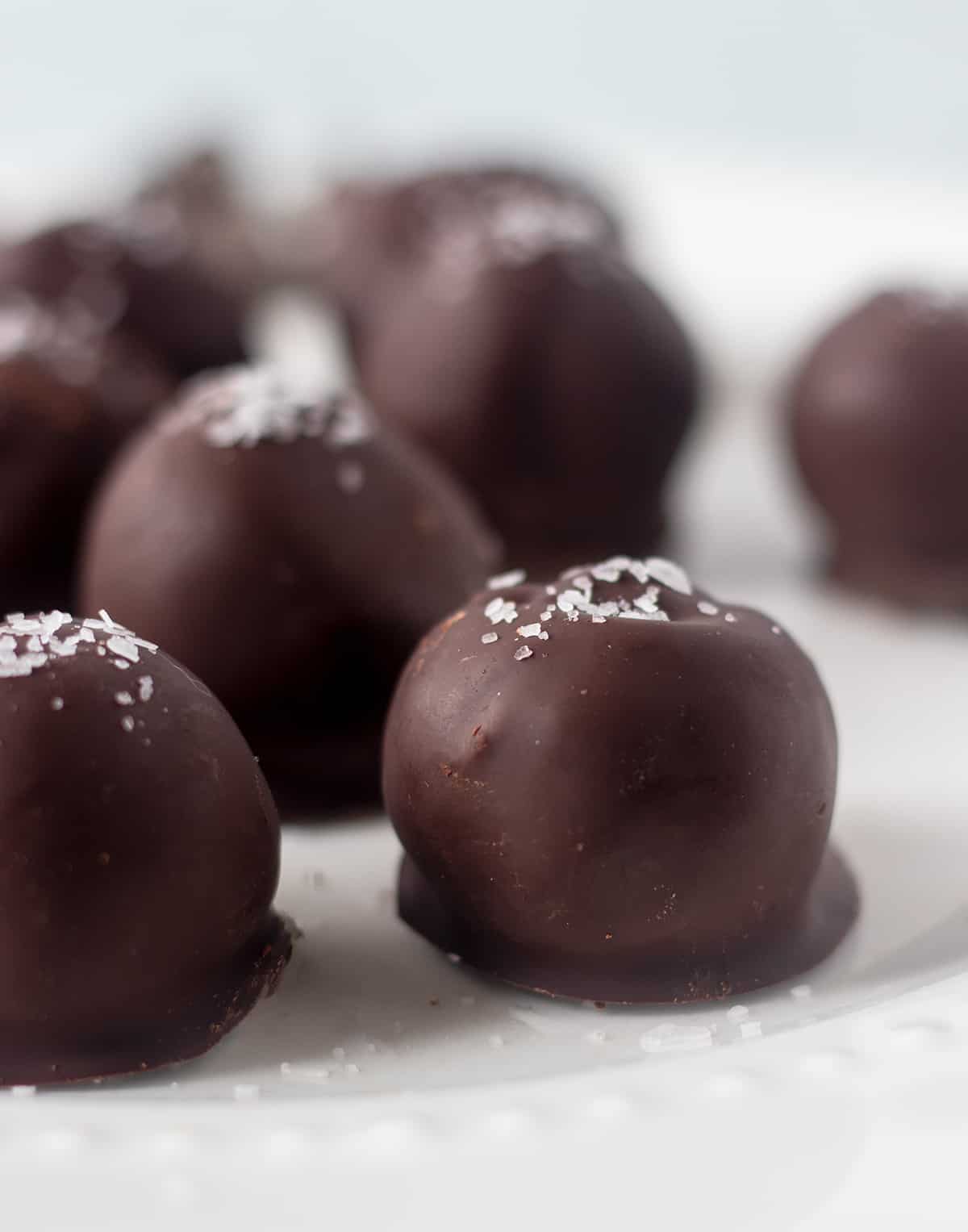 dark chocolate truffles on a white plate sprinkled with sea salt