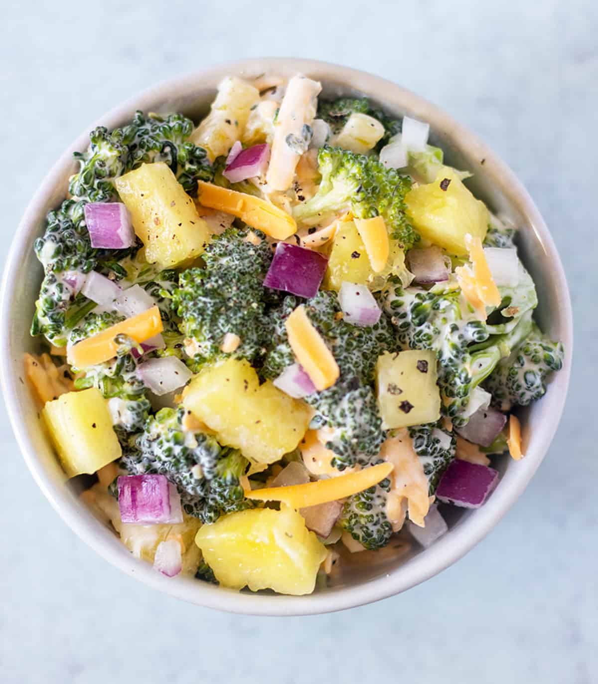 pineapple salad with broccoli and red onion and shredded cheese.