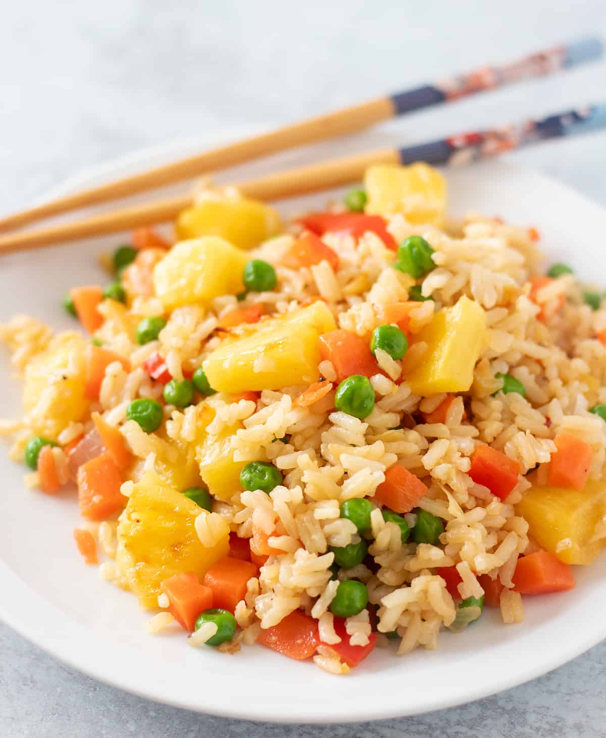 pineapple fried rice on a white plate with chopsticks for serving