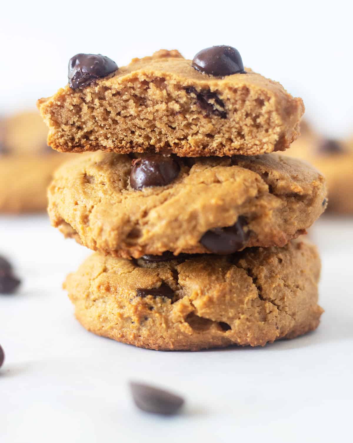 coconut flour chocolate chip cookies stacked on top of each other with the one on top cut in half.