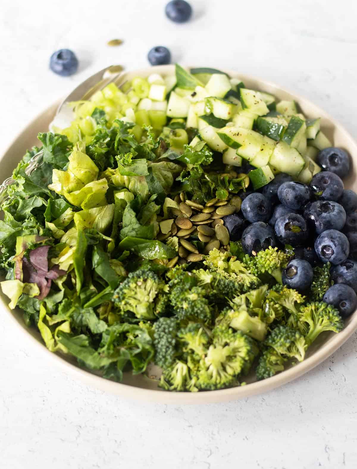 superfood salad in a white salad bowl with a silver fork sprinkled with freshly ground black pepper.