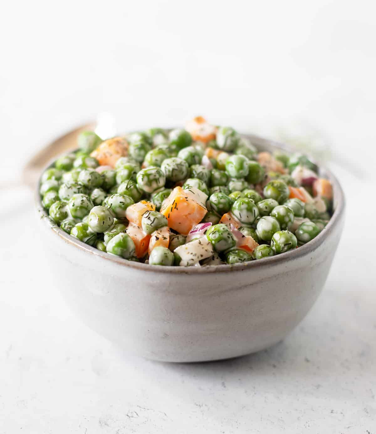 pea salad in a grey bowl garnished with dill weed.