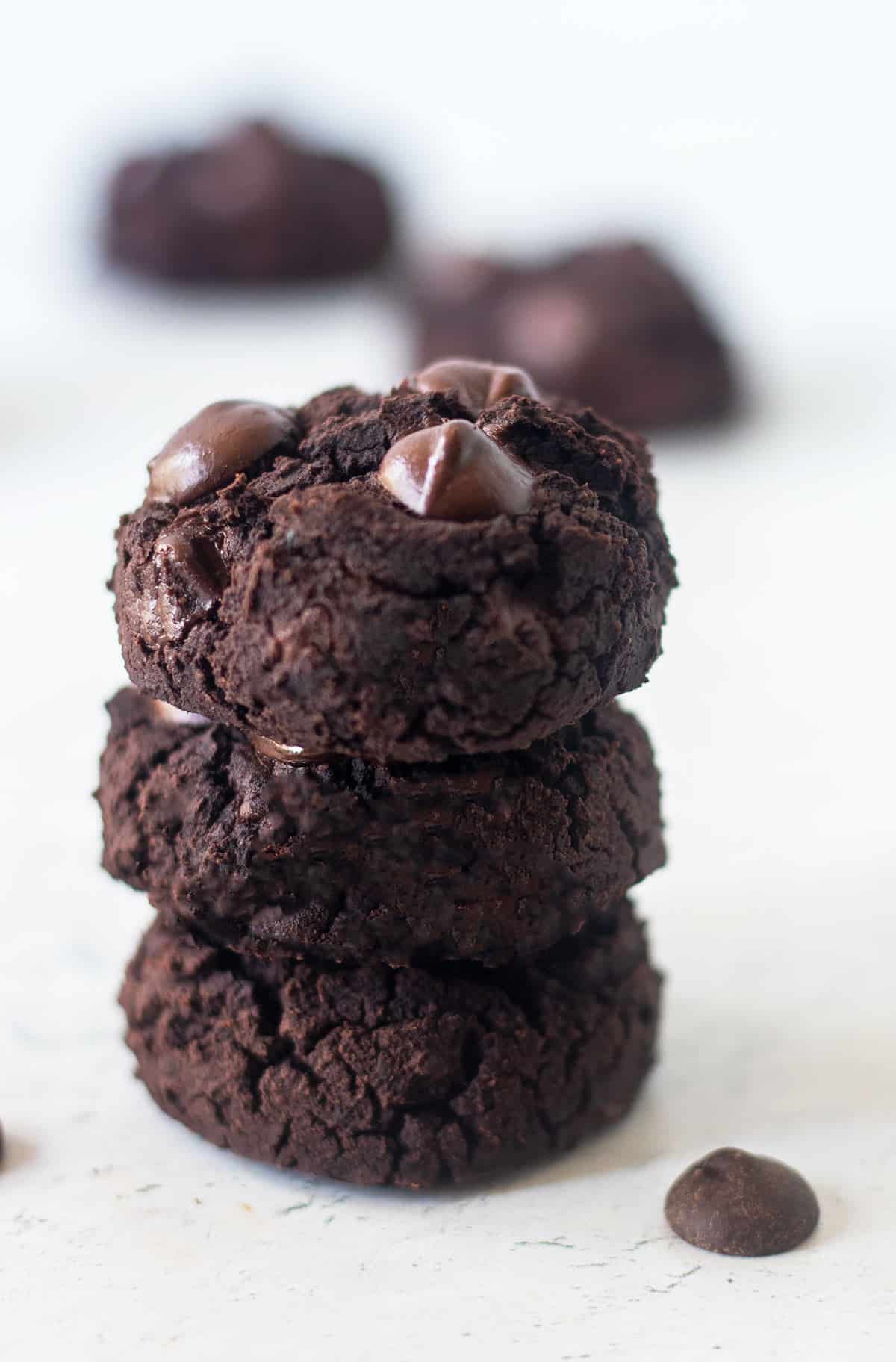 Three Black bean cookies stacked on top of each other and topped with extra chocolate chips.