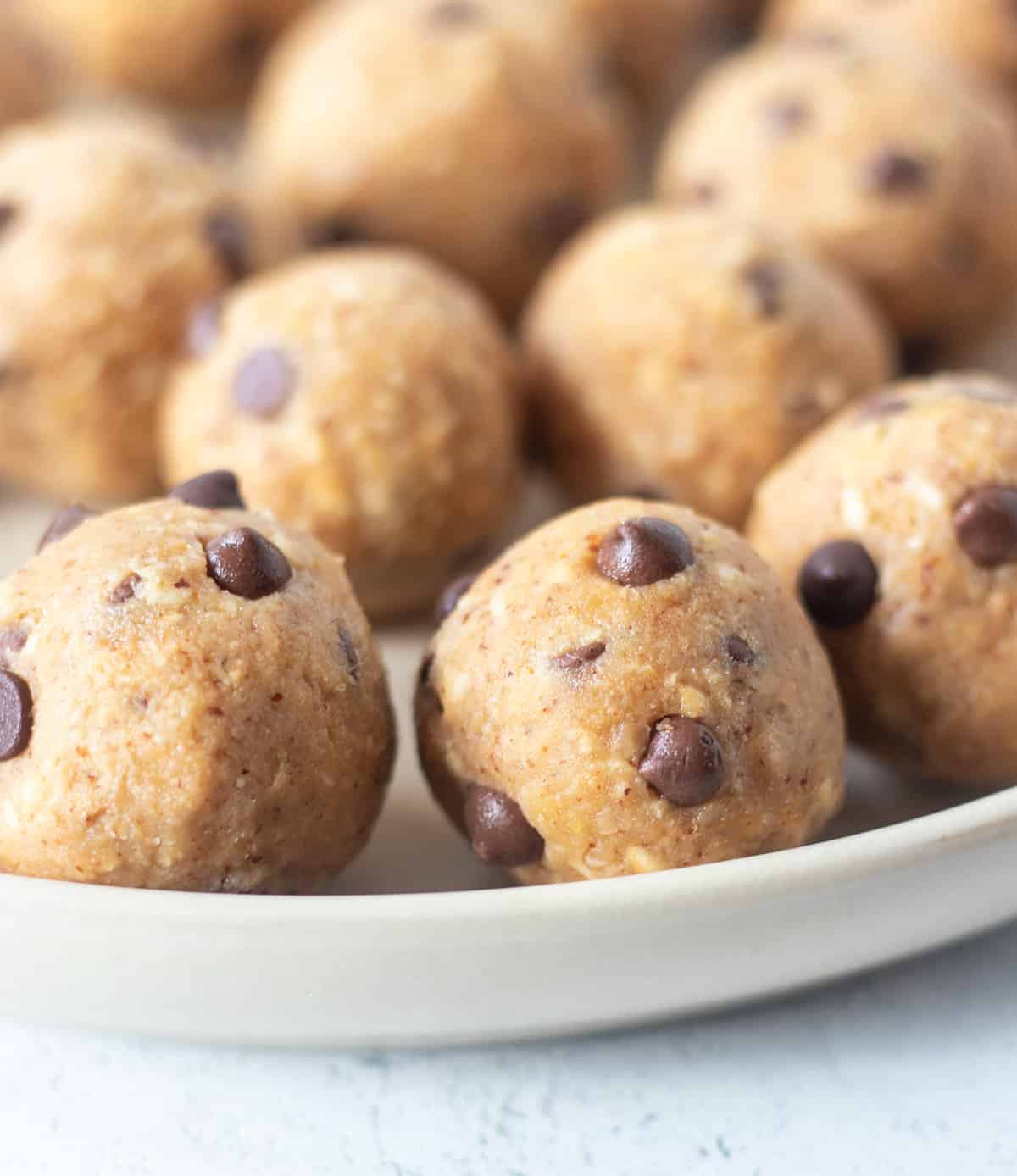 chickpea cookie dough bites on a white plate with mini chocolate chips.