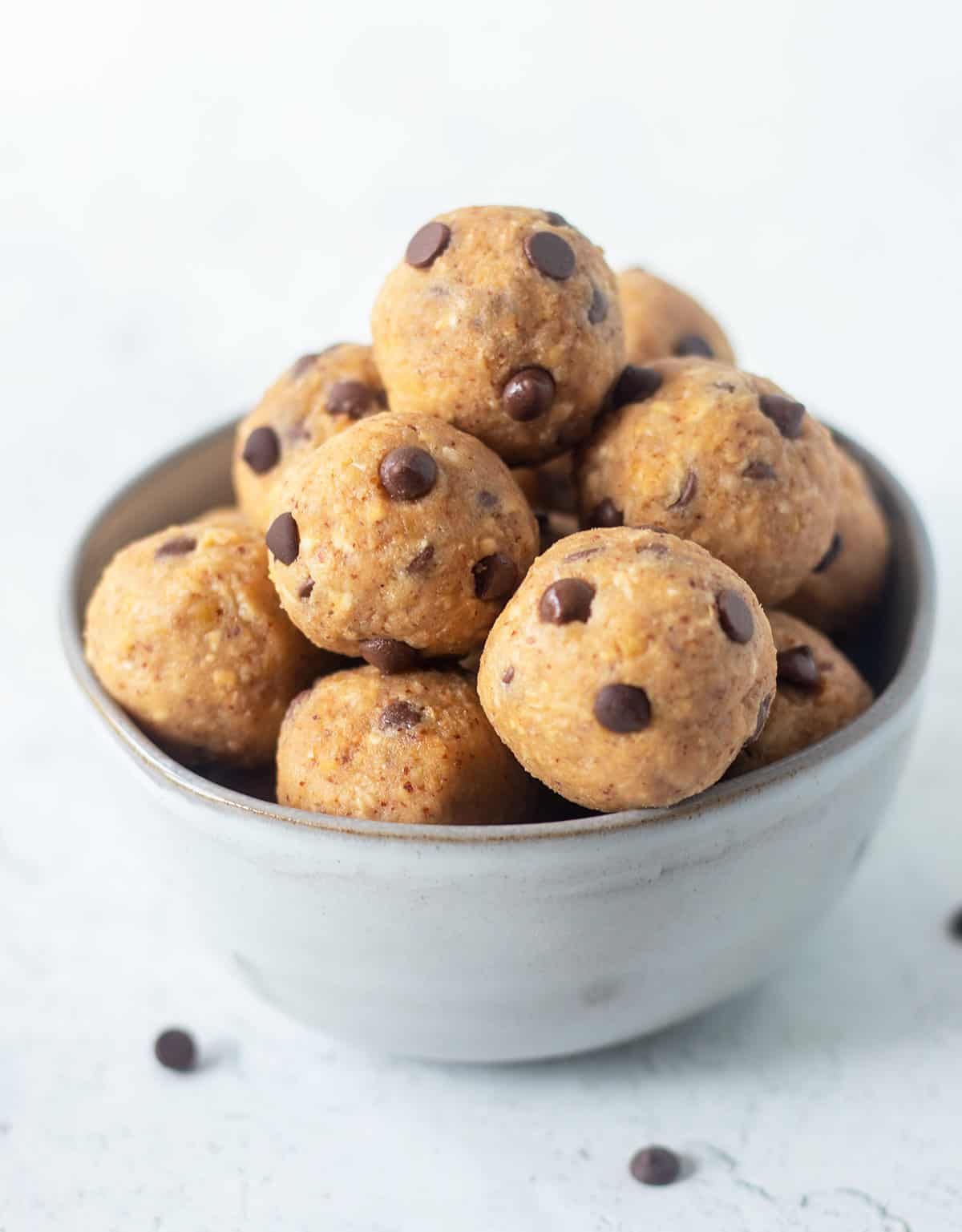 Chickpea cookie dough bites in a grey bowl that are topped with mini chocolate chips.