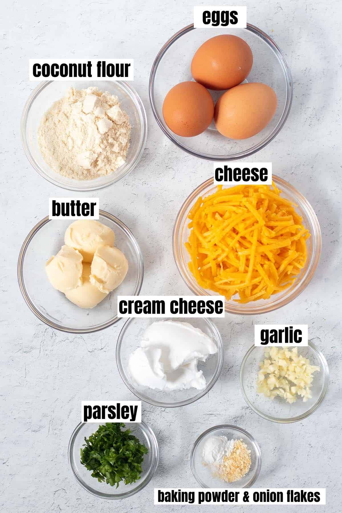 ingredients in cheesy coconut flour biscuits which include coconut flour, eggs, butter, cheese, cream cheese, garlic, parsley, baking powder & minced onion.