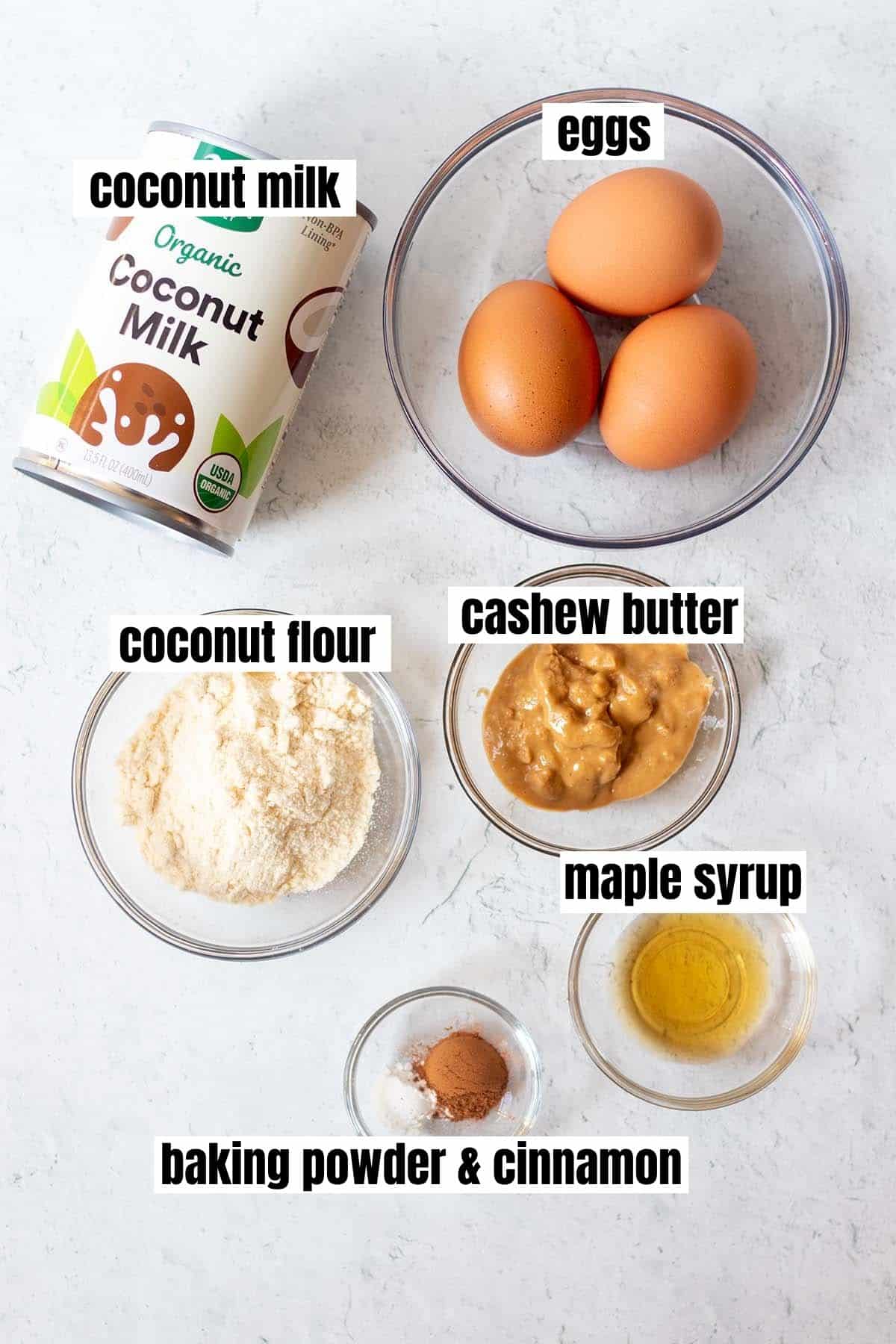 ingredients in coconut flour pancakes which include coconut milk, eggs, coconut flour, nut butter, maple syrup, baking powder and cinnamon.