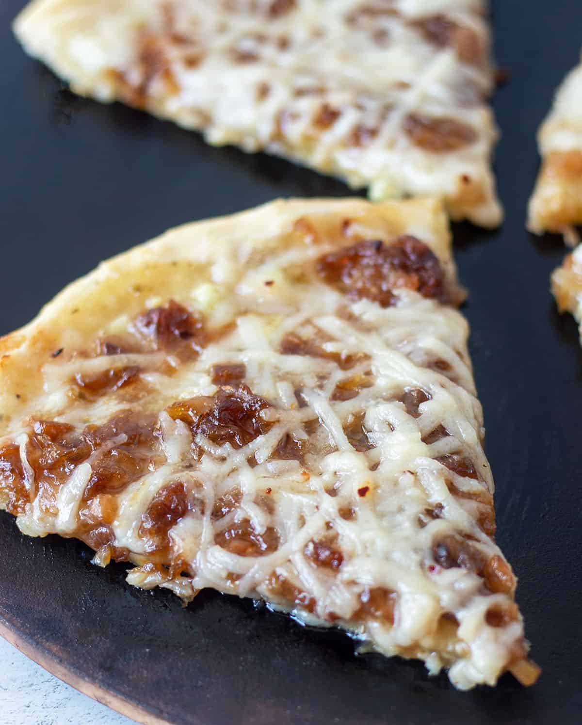 Caramelized Onion Pizza cut into slices on a pizza stone.