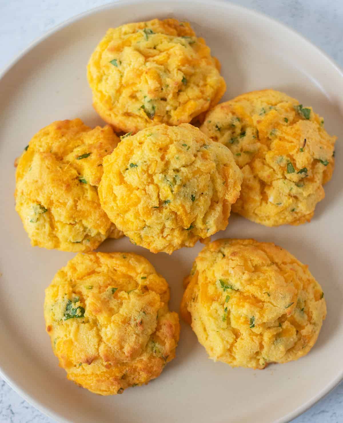 keto coconut flour biscuits with cheddar on a beige plate.