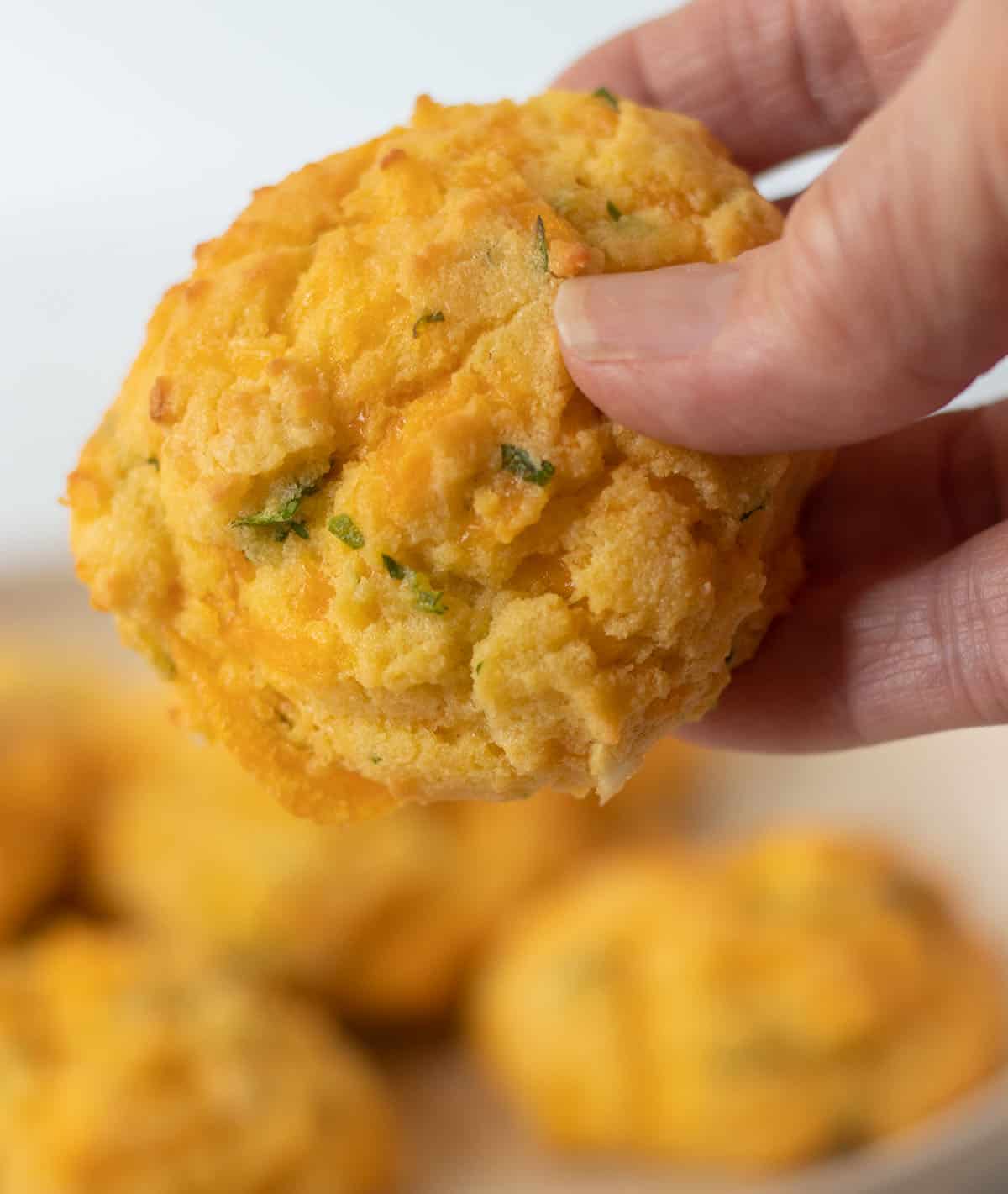 holding a cheddar coconut flour biscuit in a hand.