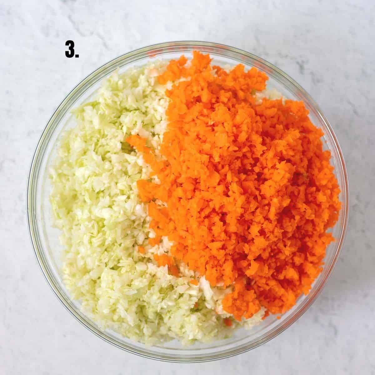 shredded cabbage and carrots in a clear glass mixing bowl