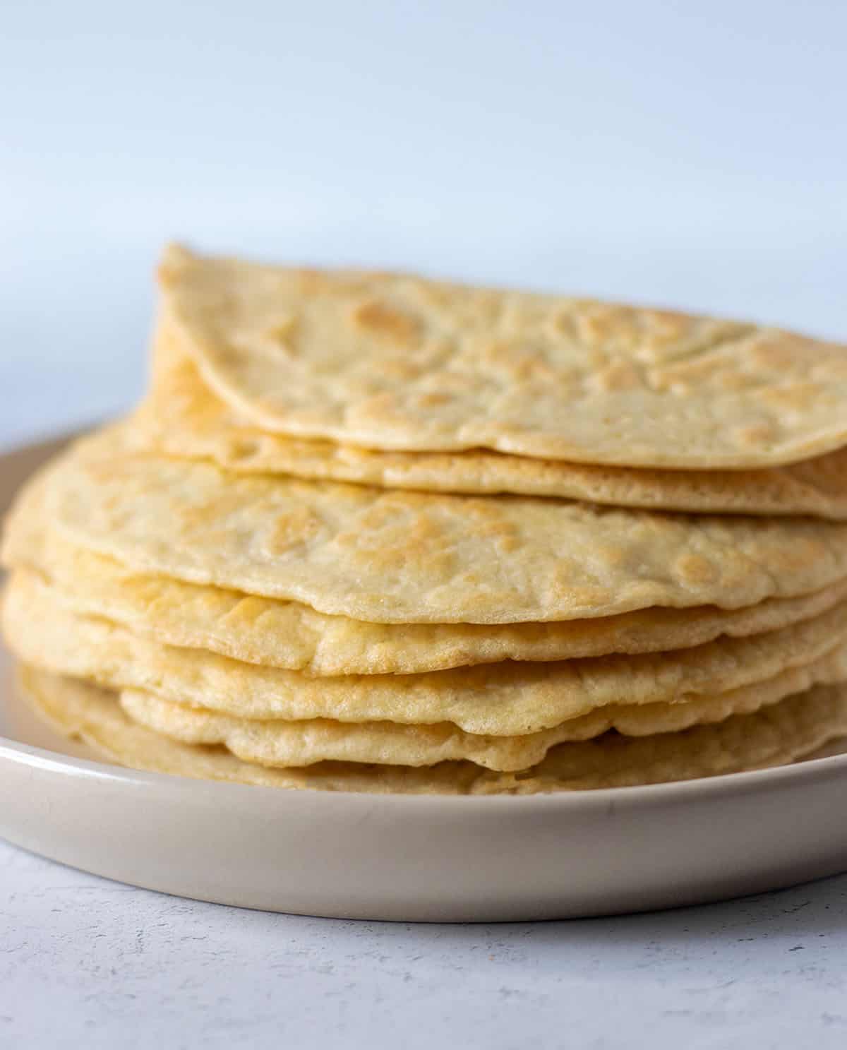almond flour tortillas stacked on a beige plate.
