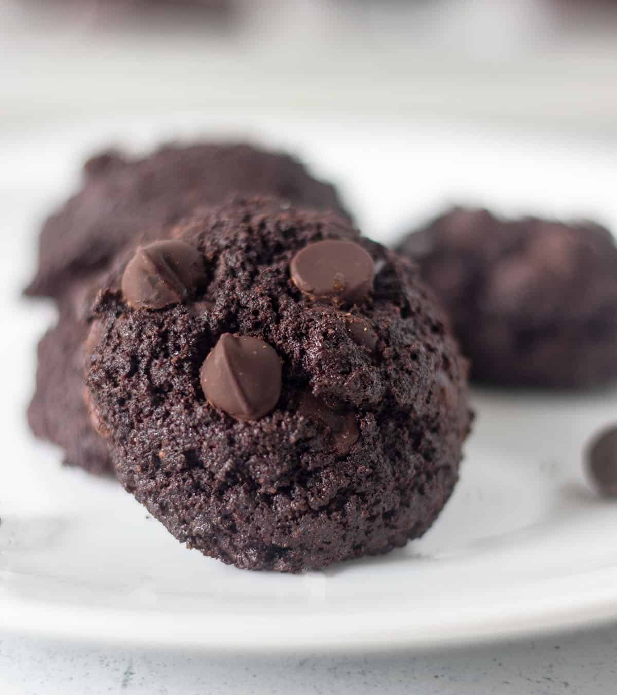chocolate coconut flour cookies served on a white plate topped with extra chocolate chips.