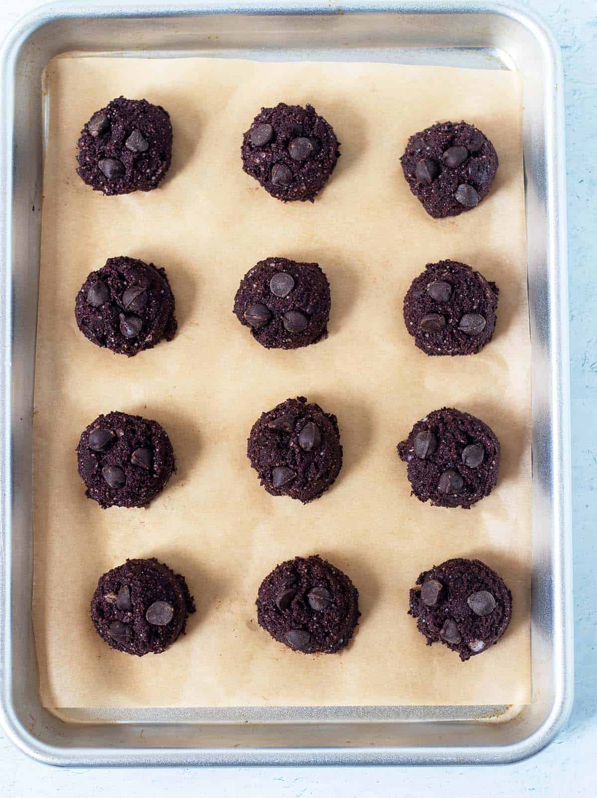 chocolate coconut flour cookies recipe on baking pan prior to being baked topped with extra chocolate chips.