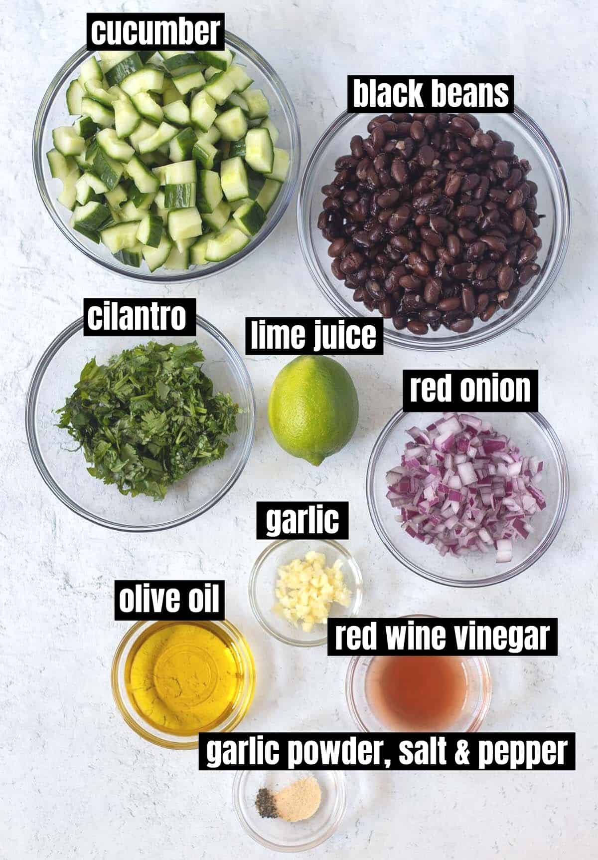 ingredients for cucumber black bean salad which include diced cucumbers, black beans, cilantro, lime, red onion, garlic, olive oil, red wine vinegar & seasonings.