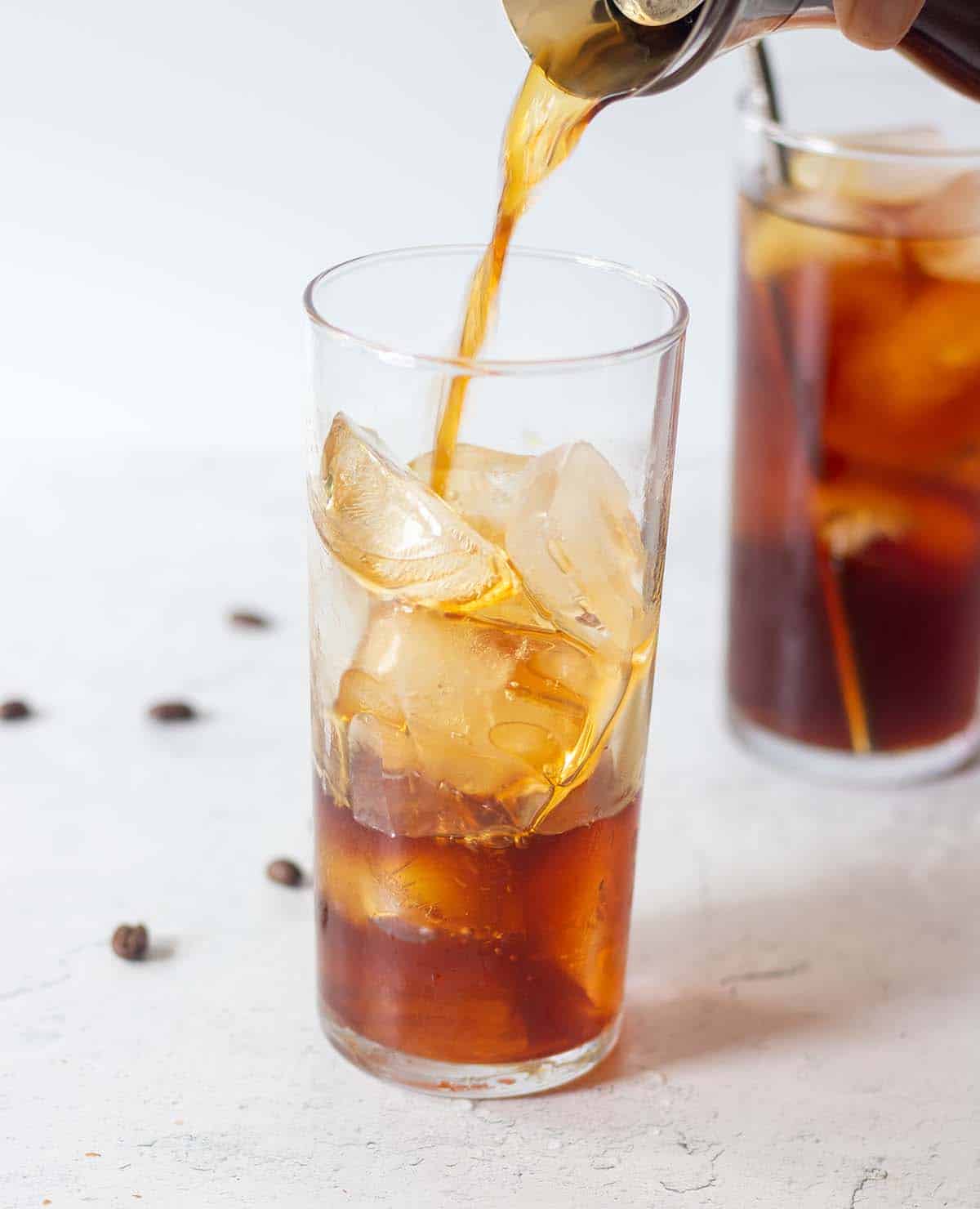 cold brew coffee being poured in a glass with ice.