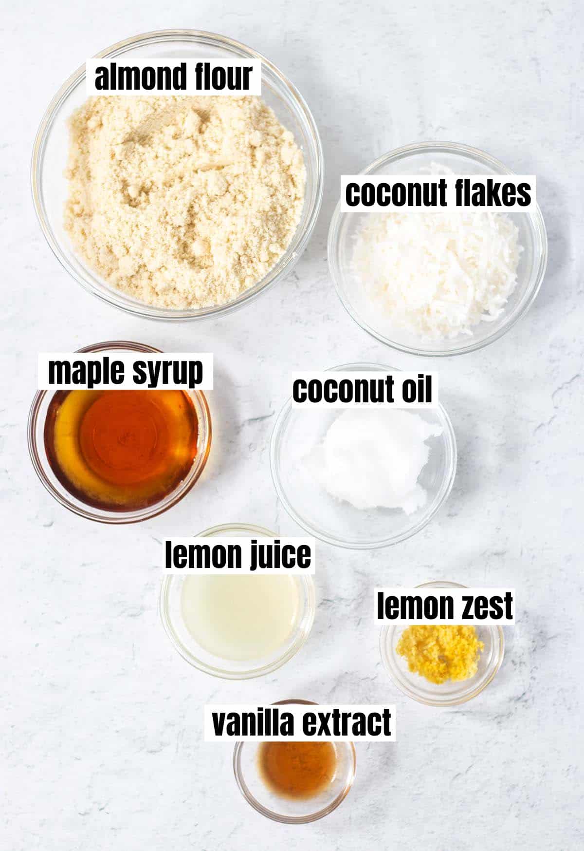 ingredients used in soft lemon cookies including almond flour, coconut flakes, maple syrup, coconut oil, lemon juice, lemon zest, vanilla extract.