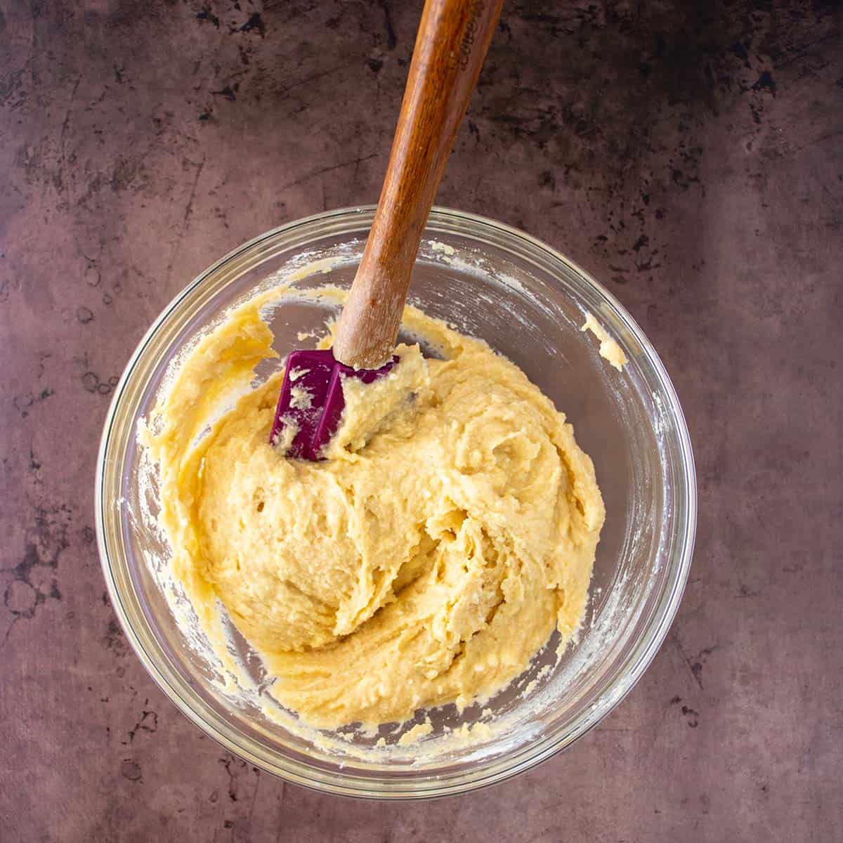 wet ingredients combined with dry with a spatula in a mixing bowl.