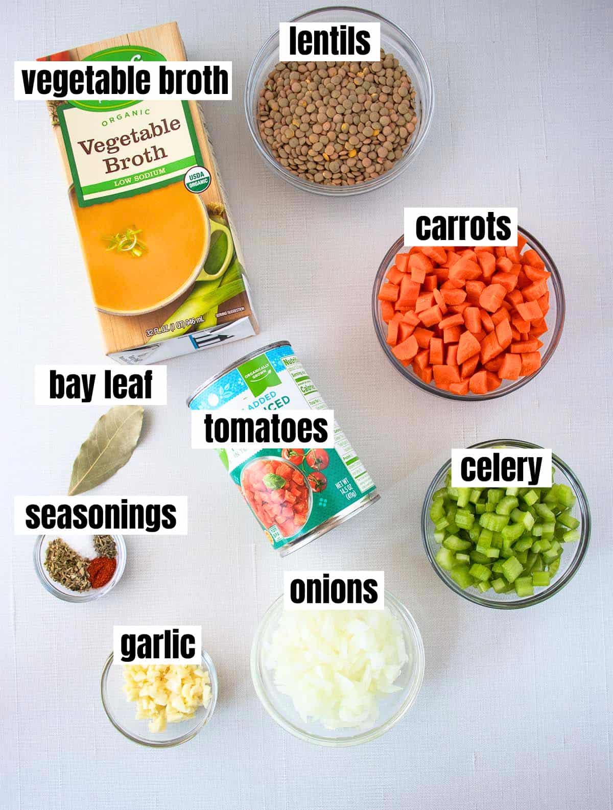 ingredients in slow cooker lentil soup which include green lentils, vegetable broth, carrots, celery, onions, garlic, canned diced tomatoes, seasonings, bay leaf.