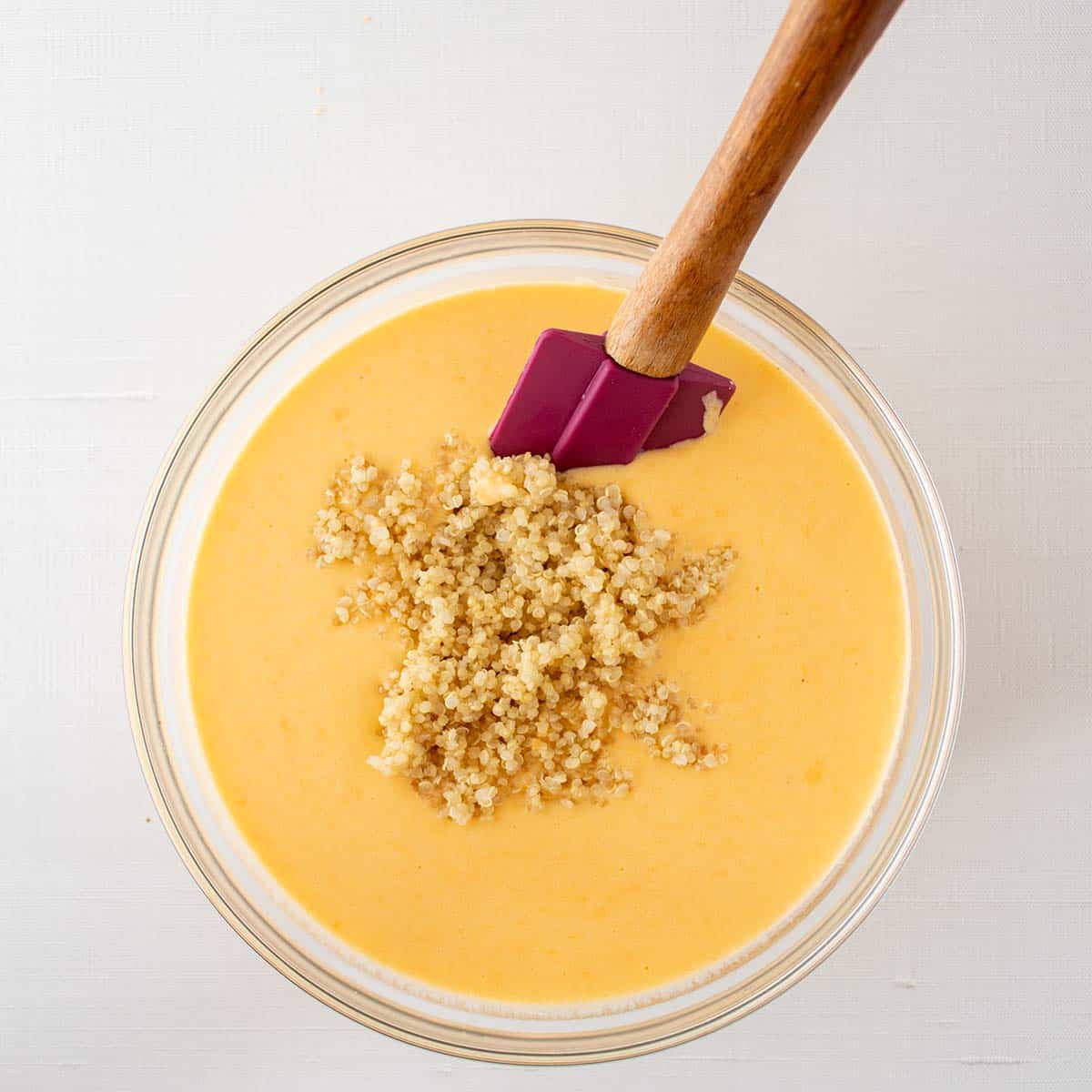 cheese sauce poured into bowl of cooked quinoa.