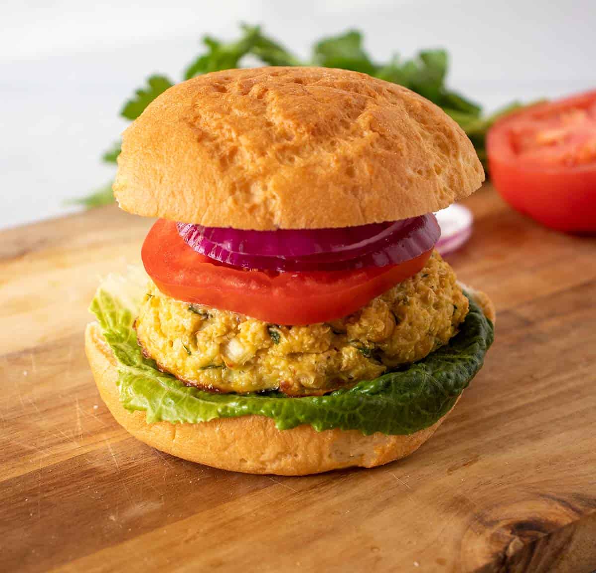 Chickpea burgers on a bun topped with lettuce, tomato, and red onion.