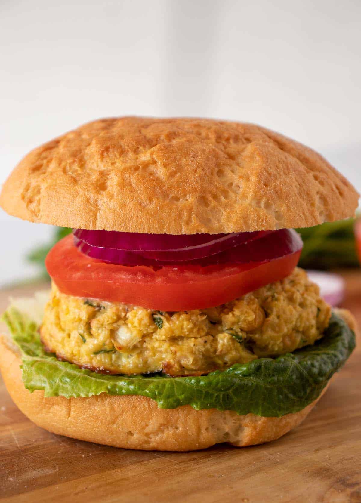 Chickpea burgers on a bun  with lettuce, tomato and red onion.