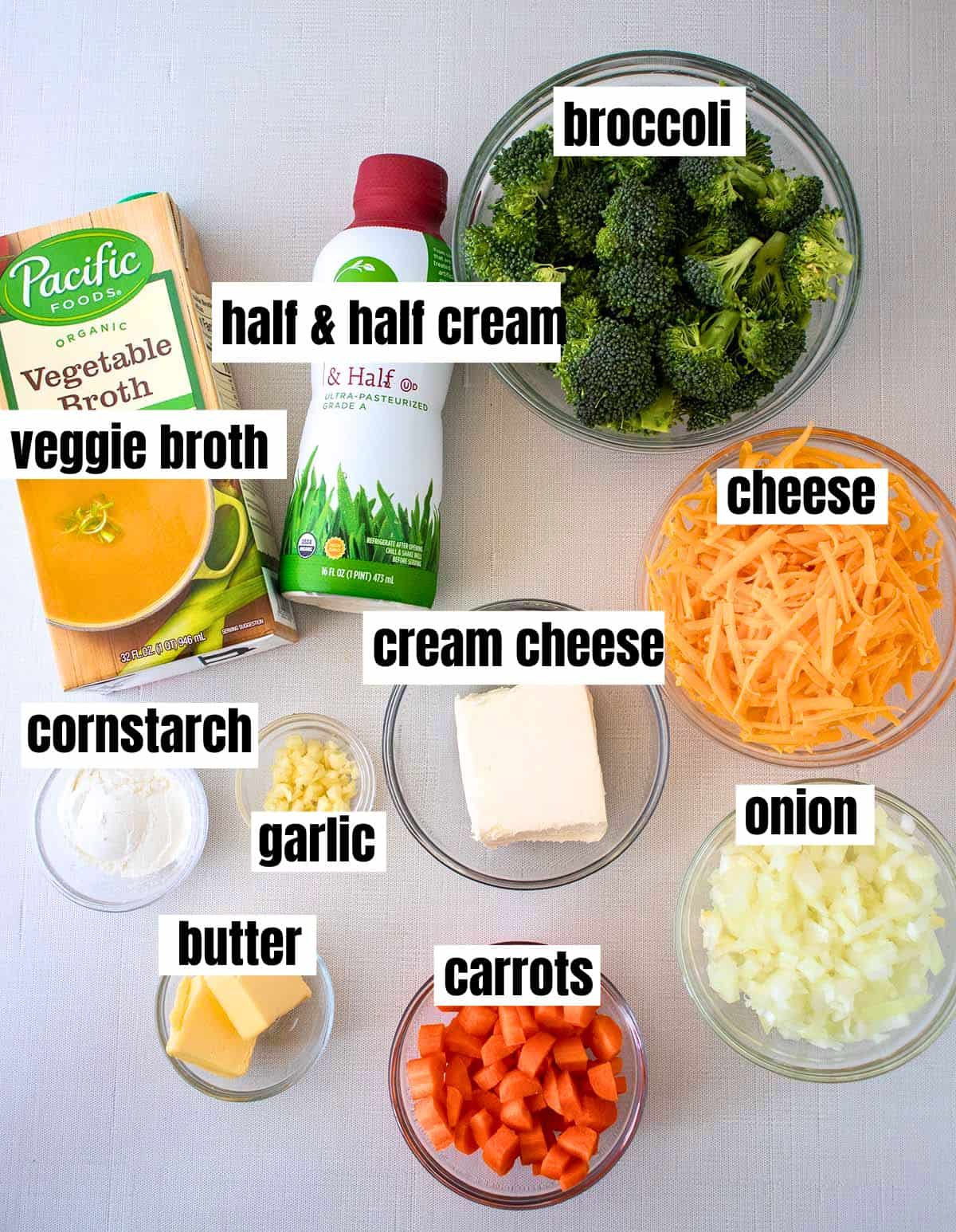 Ingredients for easy broccoli cheddar soup which include vegetable broth, half & half cream, broccoli, cheese, cream cheese, cornstarch, garlic, onion, butter and carrots.